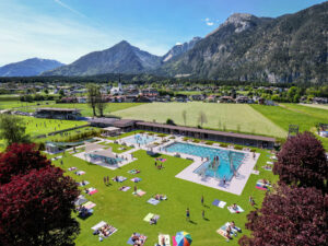 Fotorealistische 3D-Visualisierung aus der Vogelperspektive einer Freibadanlage mit Schwimmbecken, Liegewiese und Bergkulisse von Viewture